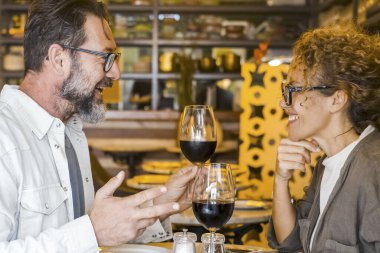 Mutlu çift restoranda gülümsüyor ve konuşuyor kırmızı şarap içiyor evli çift kafeteryada öğle yemeği molası veriyor hafta sonları dışarı çıkan bir erkekle bir kadının yaşam tarzı konsepti.