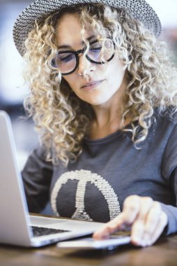 Kafede ya da havaalanı kapısında bilgisayarla çalışan bir kadının portresi. Dijital göçebe ve modern işçi. Alternatif ofiste not defteri ve telefon kullanan kadınlar. Gözlüklü güzel bayan.