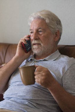 Ciddi bir son sınıf öğrencisi telefon görüşmesi yapıyor. Akıllı telefonuyla evde oturuyor. Üzücü bir duygu. Yaşlı insanlar evde yalnız.