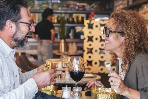 ハッピーカップル笑顔とハンバーガーとチップを食べるパブレストランで話す カフェバーでランチ休憩をしている夫婦 週末に出かける男性と女性とのライフスタイルのコンセプト — ストック写真