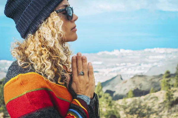 Close-up of calm young Caucasian woman holding hands on heart chest and feeling grateful and grateful. Happy female shows gratitude, love and care, prays or displays. Religion, faith concept.