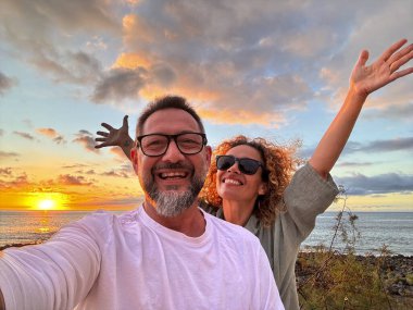 Happy adult traveler enjoy sunset in tropical destination beach together having fun and taking selfie picture to share on social media. Traveler influencer lifestyle. People summer holiday vacation