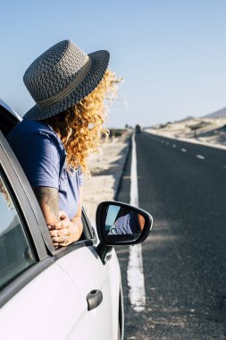 Seyahat sırasında uzun bir asfalt yol kenarına park etmiş bir kadın. Arabasından çöl ve dağ arayan kadın yolcularla yaz gezisi konsepti.