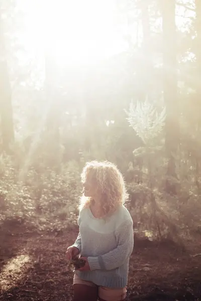 Woman walk in the woods forest alone and enjoy freedom and nature trees with sunlight sunset in background - concept of travel and discover - free people and outdoor leisure activity in nature