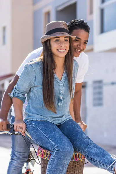 Interracial couple have fun together riding a bike in outdoor in the city - happiness and joy young people interracial boyfriend and girlfriend - two enjoy active lifestyle and love or friendship