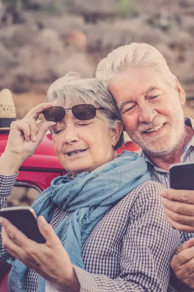 Cheerful Old Senior Couple Use Phones Together Outdoor Red Car — Stock Photo, Image