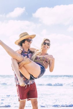Genç milenyum çifti, tropik bir ada seyahatinde sahilde tatilin tadını çıkarıyor. Erkek ve kız açık havada eğleniyorlar.