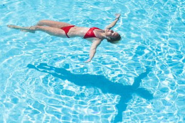 Kafkasyalı kadın dinleniyor ve otel evindeki havuzda yüzen yaz tatilinin tadını çıkarıyor - mutlu yetişkin insanlar ve tropikal lüks yaşam tarzı - kırmızı bikini