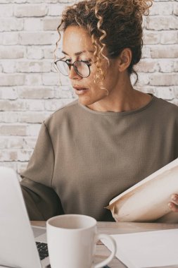 Evde bilgisayar ve kağıt kullanan olgun bir kadın. Ofisteki kadın bilgisayarla bağlantı kuruyor. Kendine güvenen kadın portresi ve modern iş aktivitesi. Stüdyodaki mimar kadın.