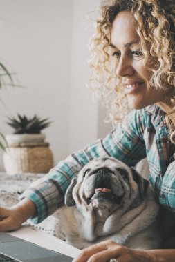 İnsanlar bilgisayarda ayaklarında köpekle çalışıyorlar. Mutlu kadın hayvan sahibi iş için dizüstü bilgisayar kullanıyor ya da internette sörf yapıyor. Sevimli köpek yavrusu, en iyi arkadaşını ararken o deftere bir şeyler yazıyor..