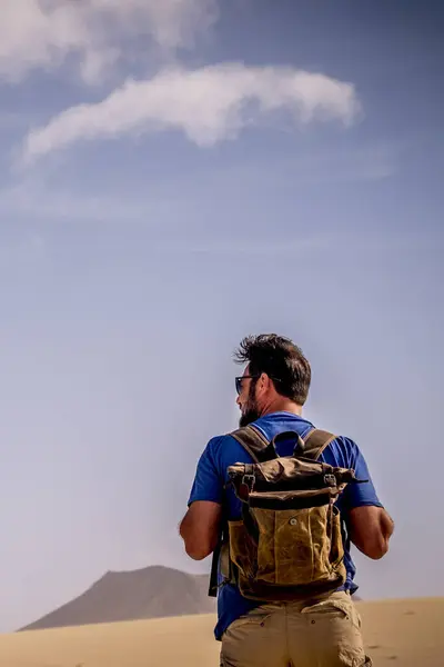 Adventure lifestyle with explorer man with backpack viewed from back walking in the desert and mountains alone - wild people alternative travel vacation alone in outdoor wild nature