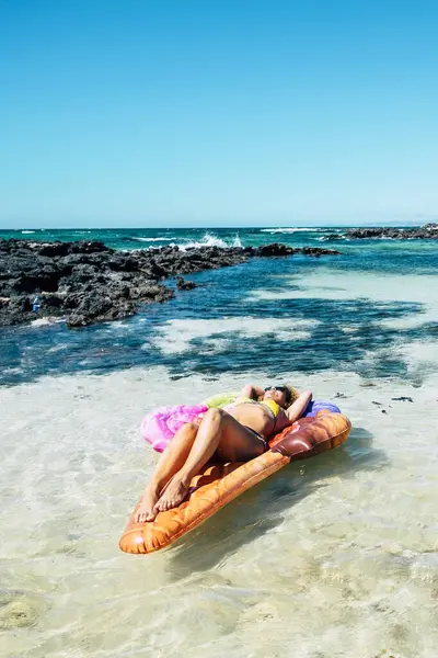 美丽的海滩和热带海水 与美丽的女人躺在一个五颜六色的充气床垫上 在暑假里悠闲地享受着大海和海滩 — 图库照片