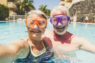 Olgun bir çift, evde havuzda eğlenirken ve eğlenirken selfie çektirirken komik bir fotoğraf çekiyor. Yaşlı, emekli bir çiftle birlikte yaz tatili aktivitelerinde mutlu mesut bir yaşam sürüyor.