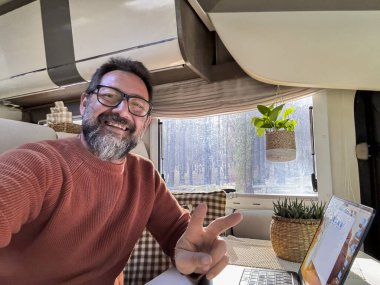 Bir karavanın içinde çalışan dijital göçebe dizüstü bilgisayar ve gezici internet bağlantısı kullanarak bir araç vanlife zarar veriyor. İnsanlar ve uzaktan kumanda işçisi. Karavanda hayat. Modern
