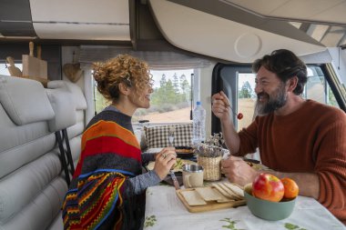 Bir karavanda masada oturup öğle yemeği yiyen ve dinlenen iki yolcu. Sakallı adam ve sarışın kadın yemek yerken konuşurlar. Seyahat kavramı yemek ve dinlenmek için durur.