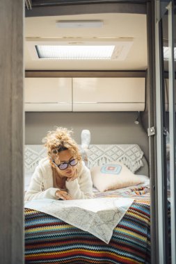 Dişi gezgin, karavan yatak odasının içinde rahatla ve bir sonraki yolculuk için kağıt yol haritasına bak. Vanlife yaşam tarzında seyahat ve macera. Minibüsteki kadın hayatı boş.