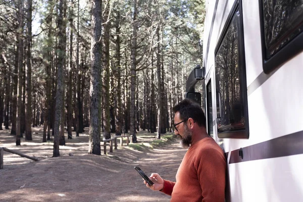 man enjoying motorhome camper van with mobile phone enjoying vanlife and alternative travel vehicle vacation holiday. Freedom.  Free parking van