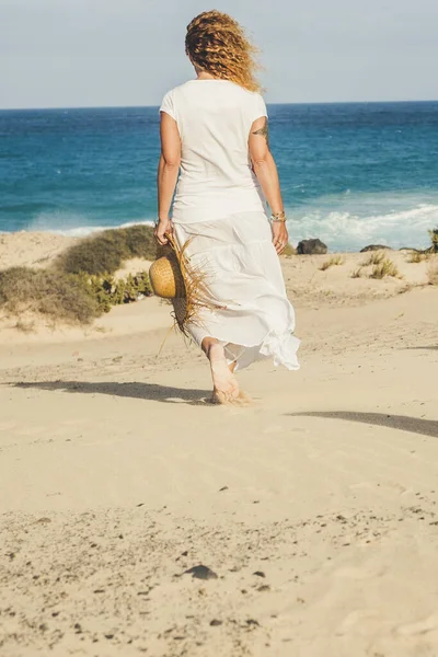 Kaukaska Kobieta Białej Sukience Oglądana Tyłu Spacerując Samotnie Piasku Plaży — Zdjęcie stockowe