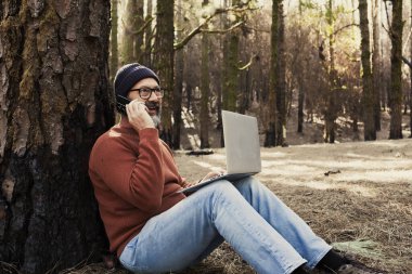 Doğa Park Ormanı 'nda teknoloji bağlantısı kullanan bir adam. Uzaktan kumandalı işçi, küçük seyahat, iş hayatı tarzı insanlar. Alternatif Doğa Ofisi 'nde çalışıyorum. Küçük bir iş. Gezginlerin iş hayatı