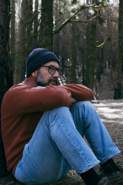 Yeşil Orman Ormanı 'nın ortasında yerde oturup rahatlayan bir adam serbest etkinliği gevşetiyor. İnsanlar ve doğa parkı hissini seviyor. Refah alternatif yaşam tarzı