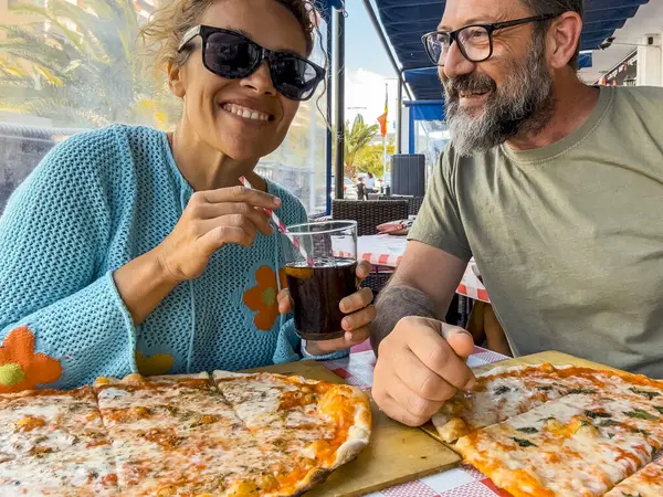 Meetings in a pizzeria. Beautiful smiling couple enjoying pizza, having fun together. Consumerism, food, lifestyle concept