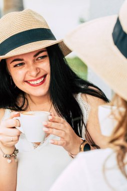 Couple of young and happy caucasian girls have fun together laughing and taking a coffee break at bar outdoor - cheerful females in friendship or relationship enjoy leisure time