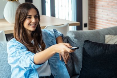 Genç bir kadın evindeki kanepede oturmuş, bir programın tadını çıkarırken elinde uzaktan kumandayla TV seyrediyor. O, evde boş zamanlarının tadını çıkarıyor. Kanepede yalnız başına film izleyen bir kadın.