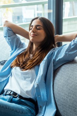 Evdeki işten sonra kanepede dinlenen bir kızın portresi, evdeki oturma odasında bir kanepede oturan. Bir genç kadın kollarını uzatıyor ve evde dinleniyor. Kanepede dinleniyor. İnsanlar