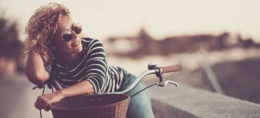 woman smile and enjoy outdoor leisure activity alone having relax on her bike. Happy female people smile and look wearing sunglasses. Healthy transport lifestyle people sustainability