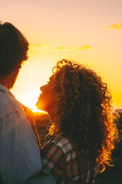 Love and romance outdoor leisure activity with man and woman hugging during golden sunset in outdoors leisure activity together. Romantic lifestyle and summer holiday vacation travel. Sunshine outdoor