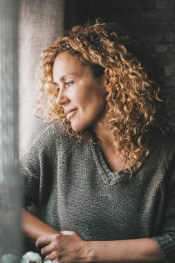 Sakin, yetişkin bir kadın, yüzünde barışçıl bir ifade ve küçük bir gülümsemeyle pencereden dışarı bakıyor. Kapalı alandaki kendine güvenen kadınlar boş zamanlarını rahat geçirirler. Hayal kuran ve düşünen bayan