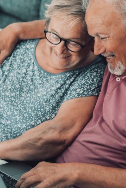 Mutlu ve neşeli yaşlı bir çift evde oturup dizüstü bilgisayarını kullanarak internet ve teknoloji aktivitelerinin tadını çıkarıyor. İnternette bilgisayar sörfü yapan ve rahatlatan modern son sınıf öğrencileri
