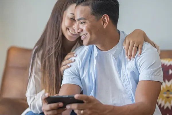 Sorrindo Jovem Casal Abraçando Enquanto Olha Para Smartphone Casal Multiétnico — Fotografia de Stock