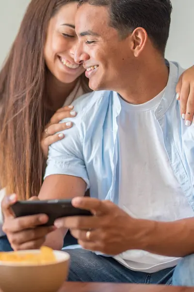 Sorrindo Jovem Casal Abraçando Enquanto Olha Para Smartphone Casal Multiétnico — Fotografia de Stock
