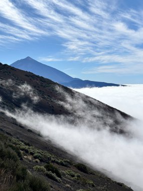Arka planda dağ manzaralı güzel bir manzara ve öndeki tepede bulutlar. İnanılmaz bir seyahat manzarası var. Mavi gökyüzü ve vahşi doğa