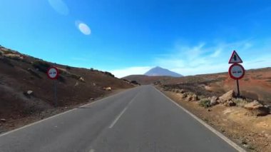 Dağ manzaralı yol boyunca araba sürüyorum. Güzel, boş bir yoldan geçen bir kameranın görüntüsü. Ulaşım ve sürücü bakış açısı kavramı. Dağ yolculuğu. Arka planda mavi gökyüzü