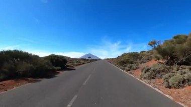 Dağ manzaralı yol boyunca araba sürüyorum. Güzel, boş bir yoldan geçen bir kameranın görüntüsü. Ulaşım ve sürücü bakış açısı kavramı. Dağ yolculuğu. Arka planda mavi gökyüzü