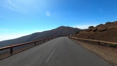 Dağ manzaralı yol boyunca araba sürüyorum. Güzel, boş bir yoldan geçen bir kameranın görüntüsü. Ulaşım ve sürücü bakış açısı kavramı. Dağ yolculuğu. Arka planda mavi gökyüzü