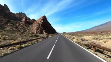 Dağ manzaralı yol boyunca araba sürüyorum. Güzel, boş bir yoldan geçen bir kameranın görüntüsü. Ulaşım ve sürücü bakış açısı kavramı. Dağ yolculuğu. Arka planda mavi gökyüzü