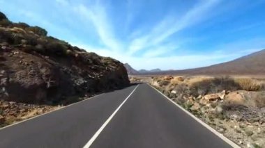 Dağ manzaralı yol boyunca araba sürüyorum. Güzel, boş bir yoldan geçen bir kameranın görüntüsü. Ulaşım ve sürücü bakış açısı kavramı. Dağ yolculuğu. Arka planda mavi gökyüzü