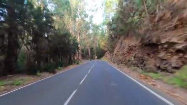 Dağ manzaralı yol boyunca araba sürüyorum. Güzel, boş bir yoldan geçen bir kameranın görüntüsü. Ulaşım ve sürücü bakış açısı kavramı. Dağ yolculuğu. Arka planda mavi gökyüzü