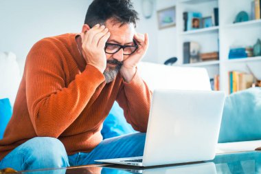 Finans hesaplamak için hesap makinesi ve dizüstü bilgisayar kullanan üzgün bir adam. Baş ağrısı vergisi, muhasebe, istatistik ve kredi analitiği olan olgun bir iş adamı. Baş ağrısı