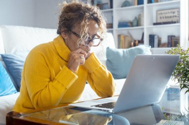 Yan görüş, bilgisayar ekranına bakan olgun, keyifli bir kadın. Mutlu orta yaşlı kadın web sörfü bilgileri, internetten yemek sipariş etmek, sosyal ağlarda sohbet etmek, oyun oynamak..