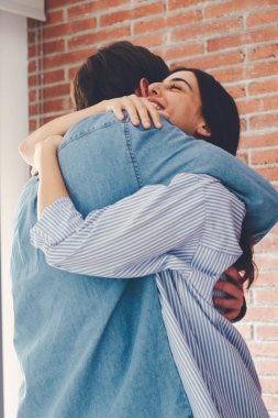 Birbirine aşık genç bir çift kırmızı tuğla bir duvarın arkasında birbirini kucaklıyor. İlişkisi olan mutlu bir çift, birlikte boş vakit geçirmekten ve sarılmaktan zevk alır. Romantik anlar, erkek ve kadın.