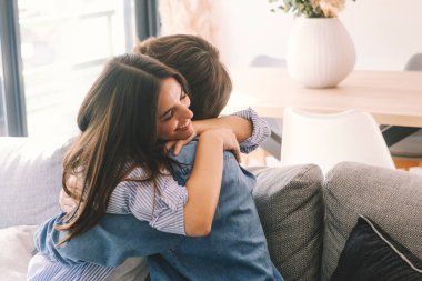 Yeni evlerinde kucaklaşan güzel genç bir çift. Nişanlı çiftler yeni evleri için birbirlerine mutlu bir şekilde sarılarak kutluyorlar. İlişki başarısını kutlayan erkek ve kadın kapalı mekanda boş vakit geçiriyor.