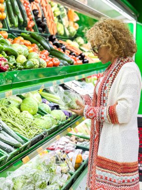 Kadın kontrolü kaliteli yemek. Market / süpermarketin üretim bölümünde meyve ve sebze alışverişi yapan güzel bir kadın (renk tonlu görüntü))