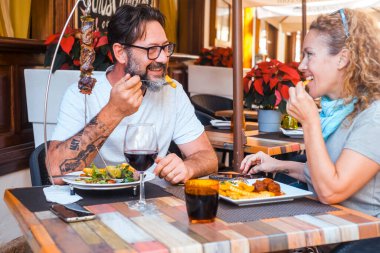 Yetişkin bir çift restoranda birlikte yemek yiyor kırmızı şarap içiyor ve mutlu bir tartışma sırasında gülümsüyor. Bir erkek ve bir kadın ilk kez çıkıyorlar. Modern yetişkin insanlar dışarıda eğleniyor.