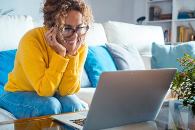 Beyaz kanepede oturan çekici bir kadın gülümseyerek dizüstü bilgisayarına bakıyor ve en sevdiği programı dinliyor. Mutlu kadın dinler ve arkadaşıyla konuşur. Teknoloji konsepti