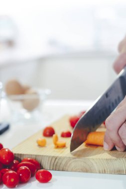 Evde taze çiğ sebze doğrayan bir bıçakla şef. Evde pişiren, sağlıklı sebze yapan, sebze doğrayan, yemek yiyen bir adam mutfakta salata hazırlıyor.