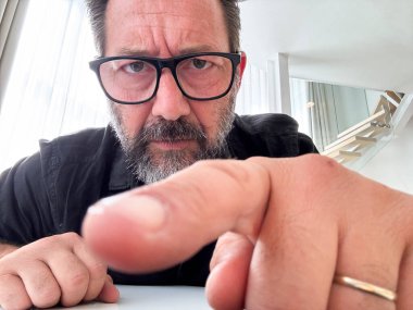 Dolandırıcılık web sitesine tıklayan bir adamın laptop kamera görüntüsü. Parmağını kapat ve arka plandaki şüphe ifadesi. Porno dolandırıcılığı güvenlik şifresi çevrimiçi sorunları. Tıklama uyarısı sorunları